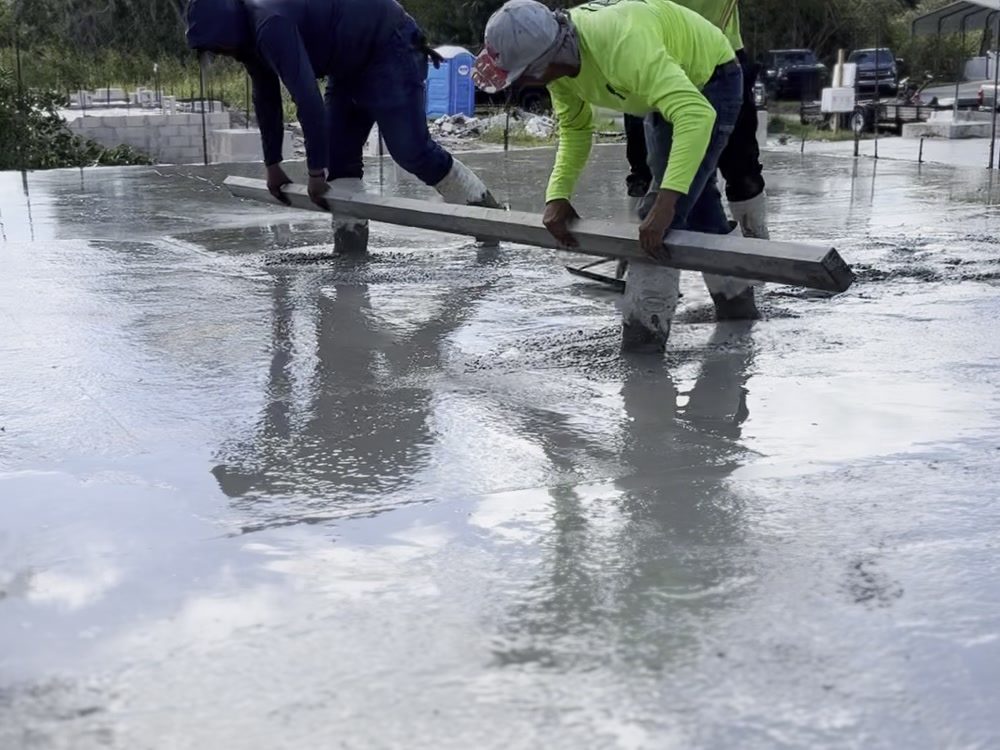 Finishers screeding a freshly poured concrete slab